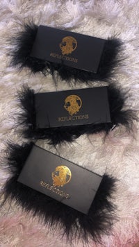three black feathered eyeshadow palettes on a furry surface