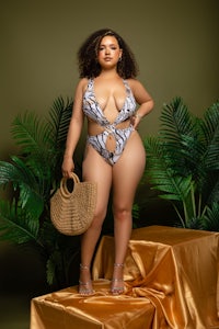 a woman in a bikini posing with a wicker basket