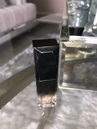 a bottle of lipstick sitting on a table next to a mirror